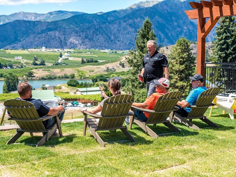 four people enjoying wine in Adirondack chairs