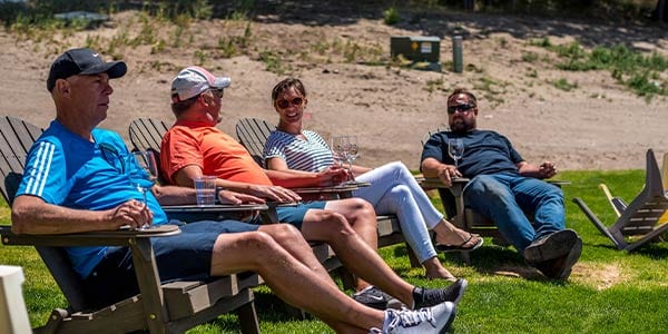 Four people enjoying wine in Adirondack chairs