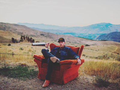 Aaron Crawford sitting on a red lounge chair in the middle of a valley