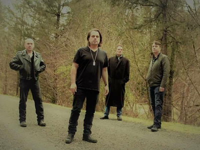 Four male band members of Vertigo Zoo standing in the woods